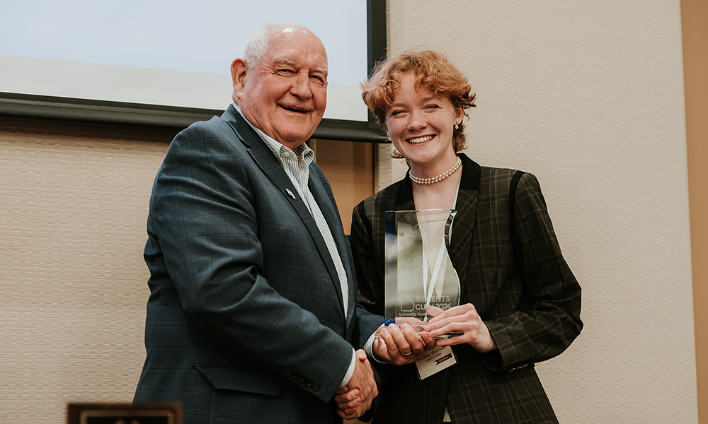 Chancellor Sonny Perdue presents a trophy to individual debater Ansley Warnock at the inaugural tournament in 2024.