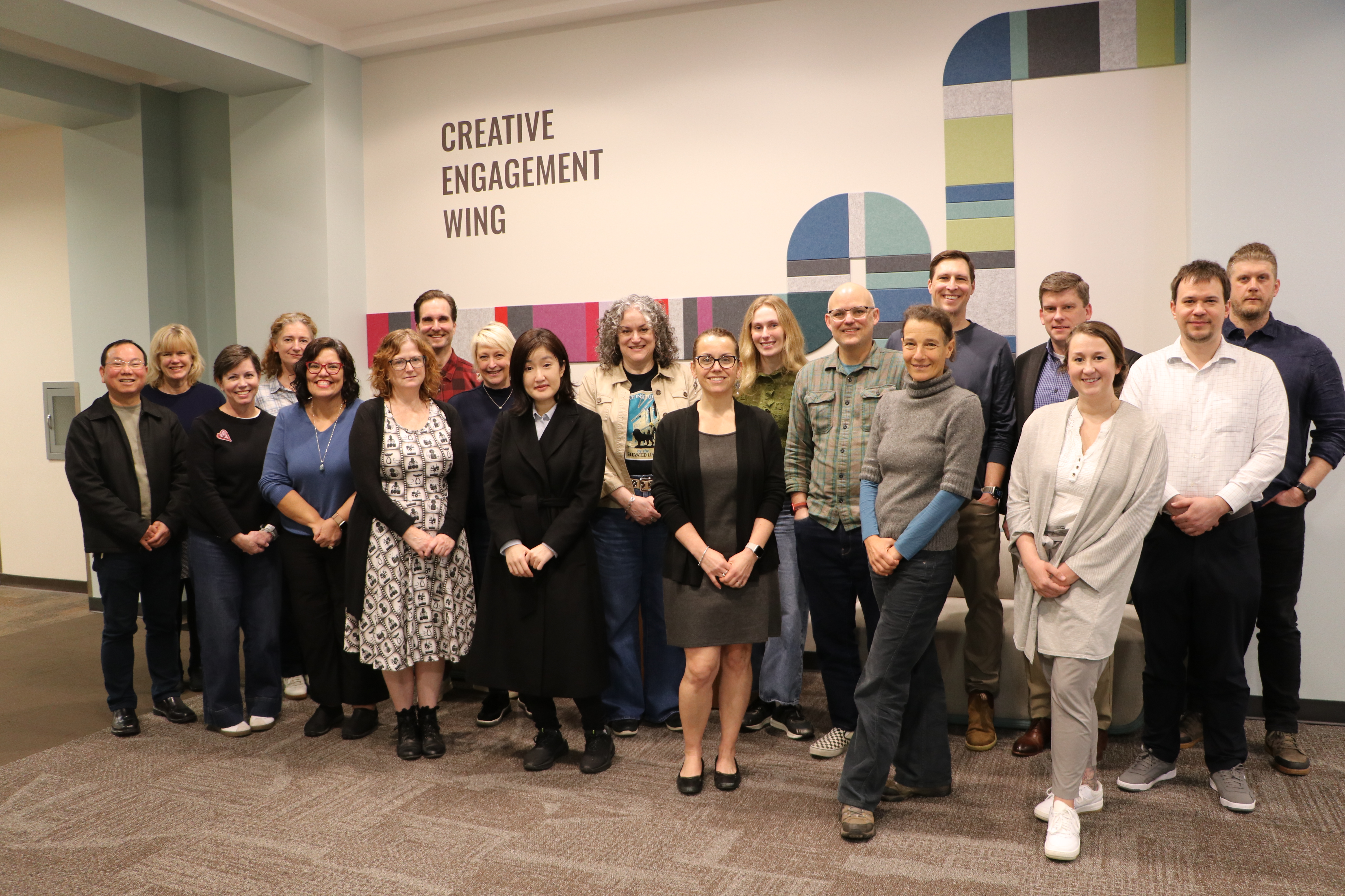 The twenty inaugural members of the Creative Engagement Wing Fellows program pose in front of a Creative Engagement Wing sign