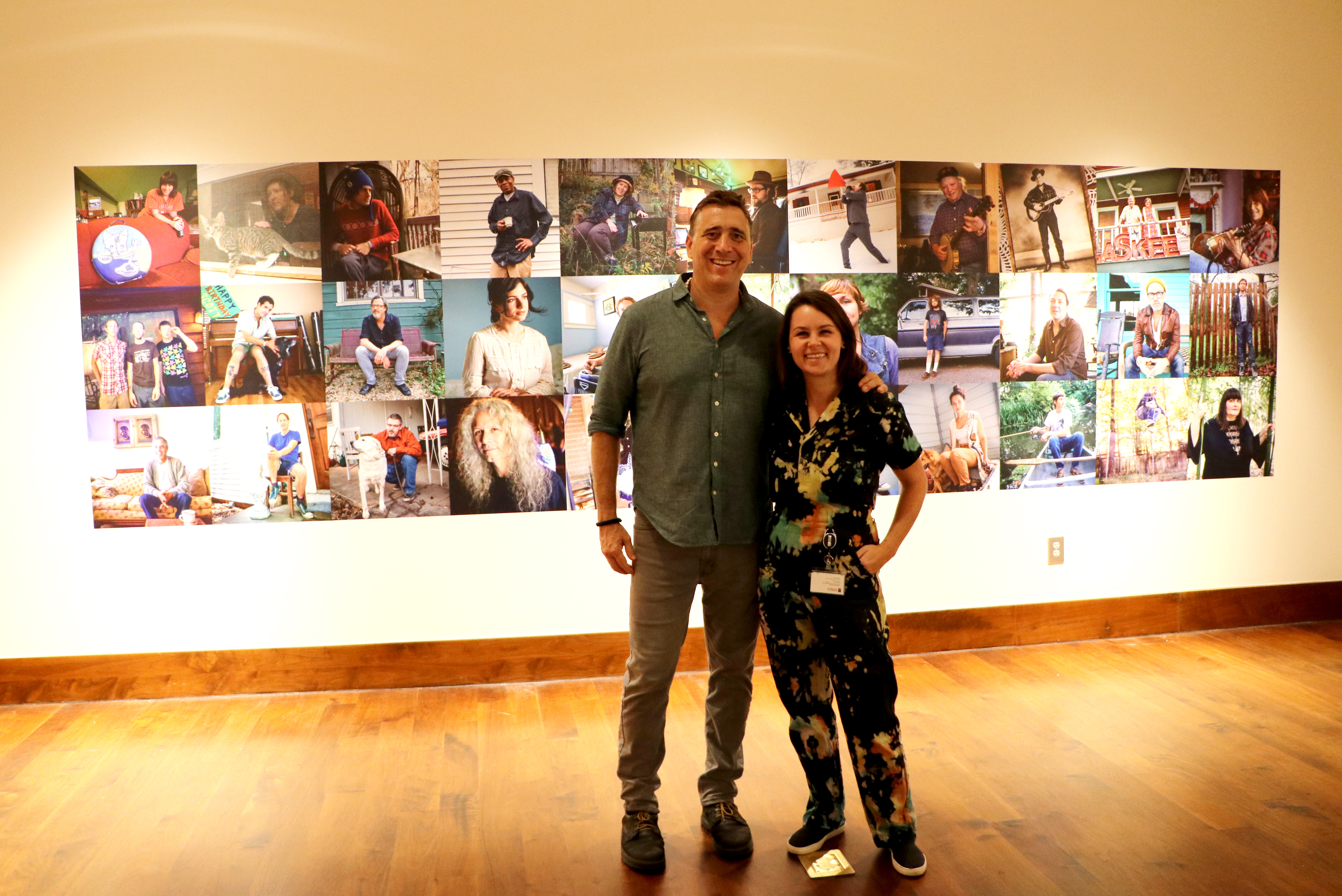 Photographer Jason Thrasher poses with curator Jan Hebbard in front of a wall of photographs of musicians