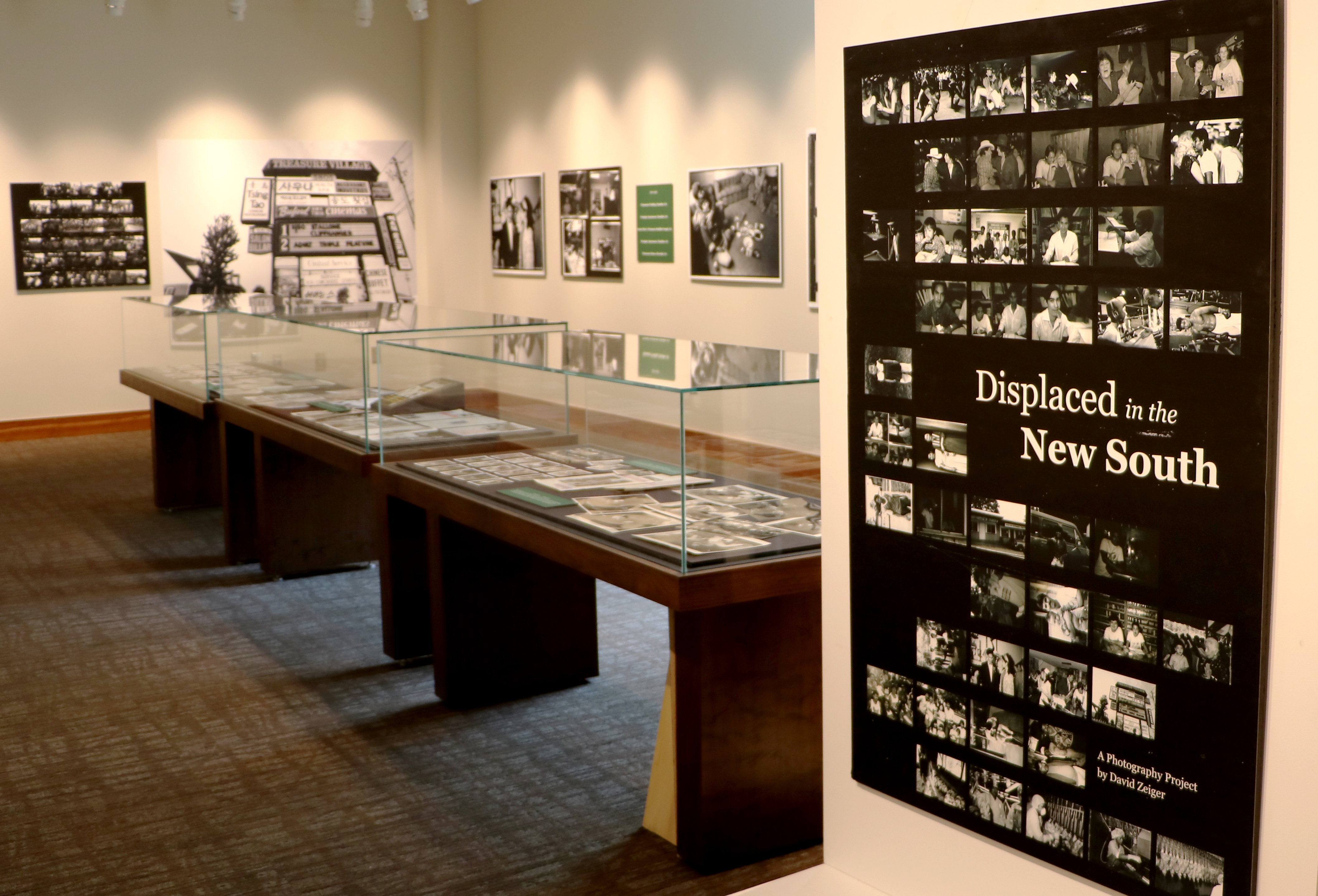 Photograph of exhibit hall with black and white photos and poster title "Displaced in the New South"