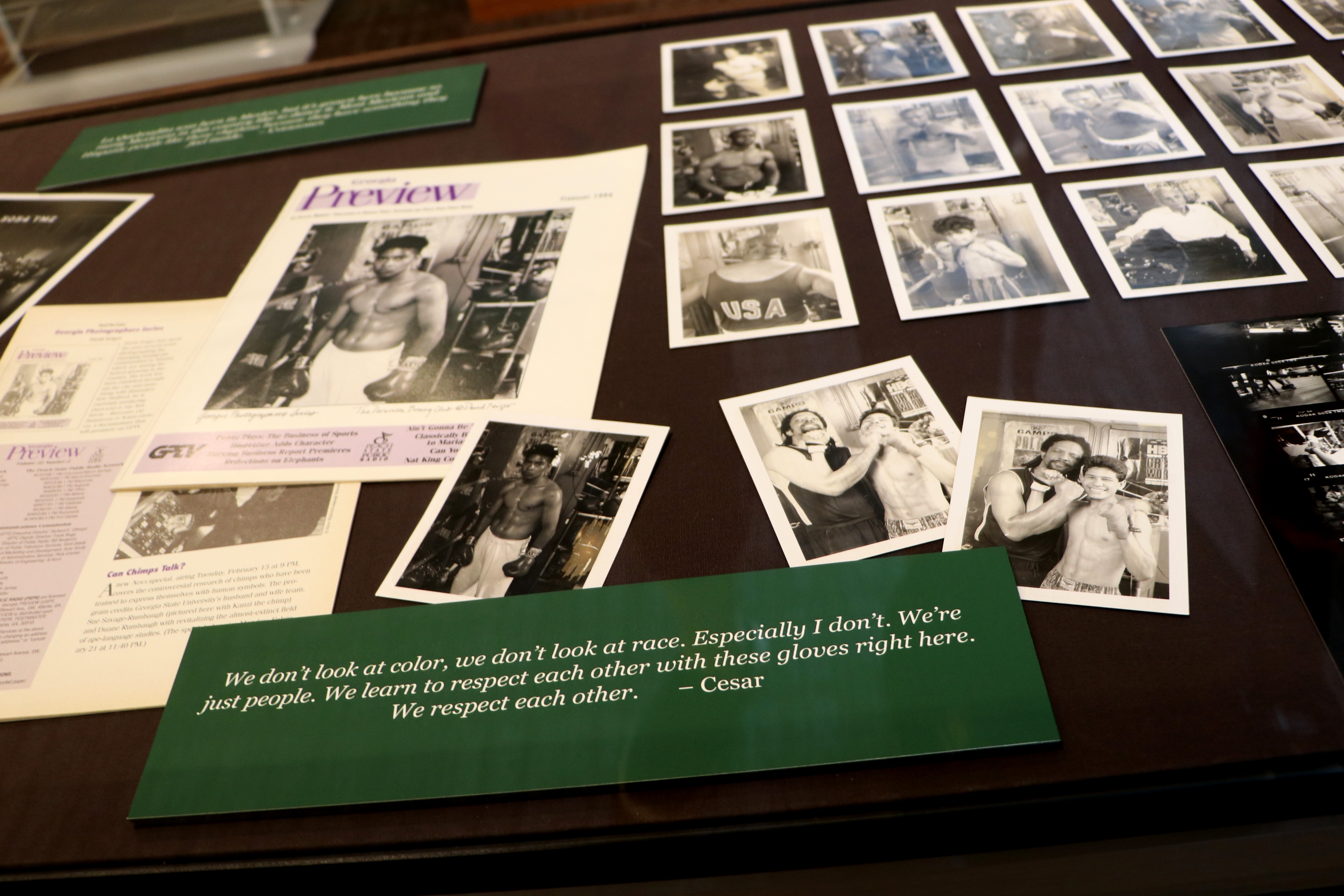 Exhibit case with black and white photos of boxers and a quote "We don't look at color, we don't look at race. Especially I don't. We're just people. We learn to respect each other with these gloves right here. We respect each other. - Cesar"