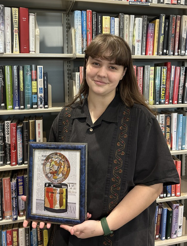 Norah Phillip holding her Libraries Undergraduate Research Award winning project