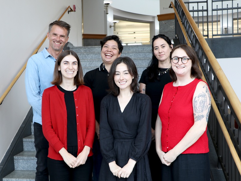 group photo of 6 librarians standing in 2 rows in front of stairs at the MLC