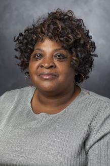 Woman with curly hair wearing a gray sweater