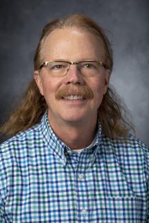 Man with long hair and mustache wearing glasses