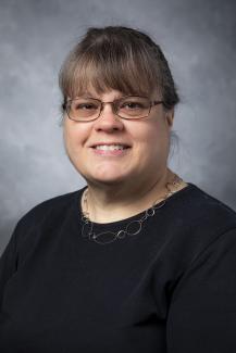 Woman with long hair pulled into a bun. She's also wearing glasses.