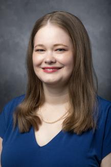 Woman with long dark blonde hair wearing a royal blue shirt.