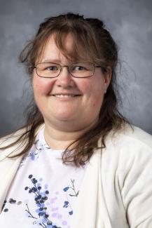 Woman in glasses wearing a floral shirt under a white cardigan