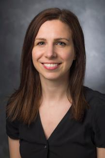 Woman with dark hair smiling and wearing a black shirt.