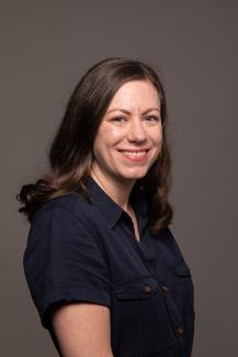 Woman with brown hair smiling and wearing a black shirt.