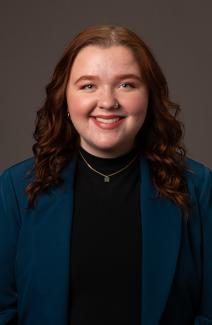 Woman with jacket and reddish wavy hair smiling