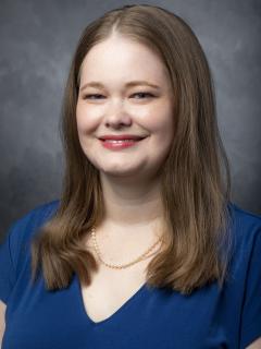 Woman with long dark blonde hair wearing a royal blue shirt.