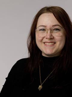 Smiling woman with dark shirt and glasses