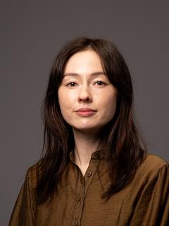 Woman with dark hair wearing an olive green button up shirt
