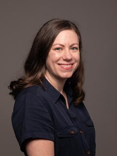 Woman with brown hair smiling and wearing a black shirt.