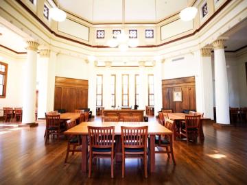 Large, beautiful wooden tables in a traditional Carnegie library setting with ornate walls and a high ceiling