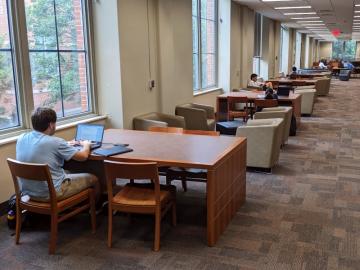 Student works at a large table in open study space 